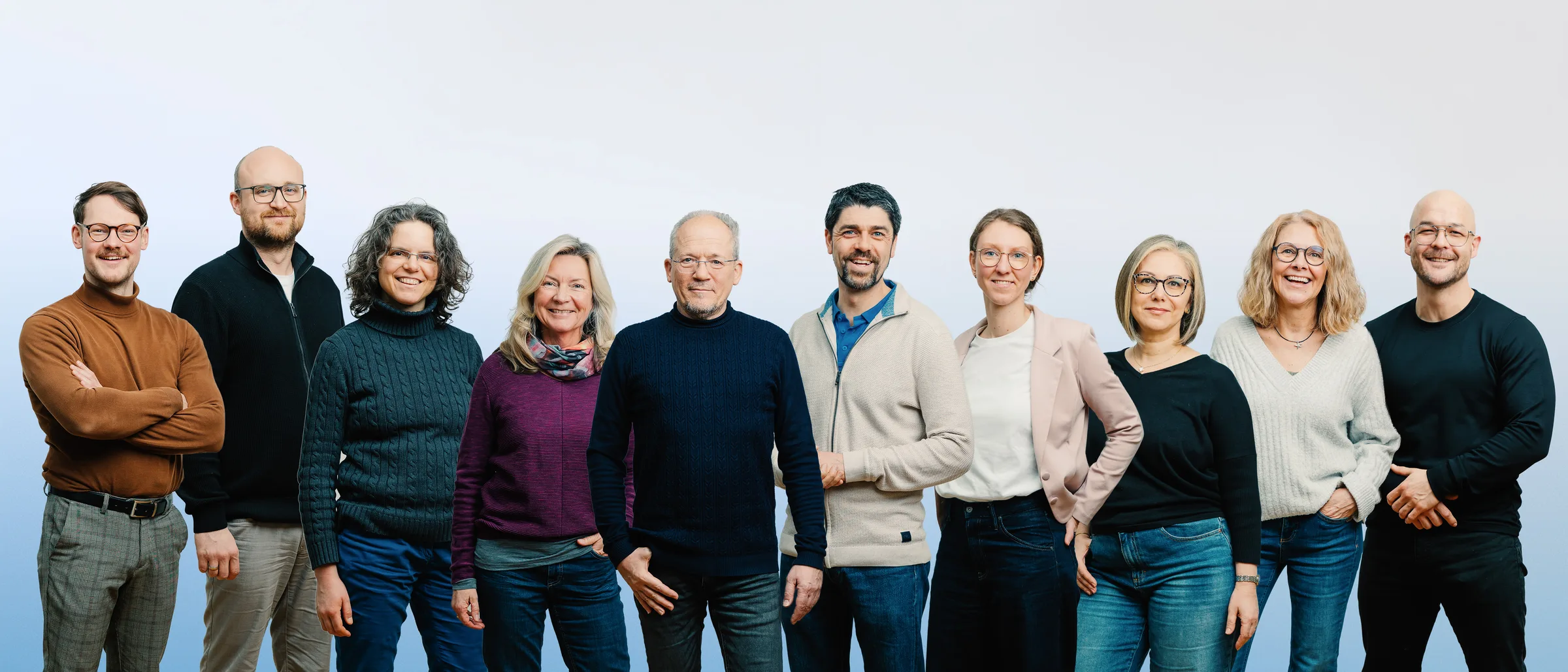 Gruppenbild des tomtrailer-Teams vor Farbverlauf-Hintergrund